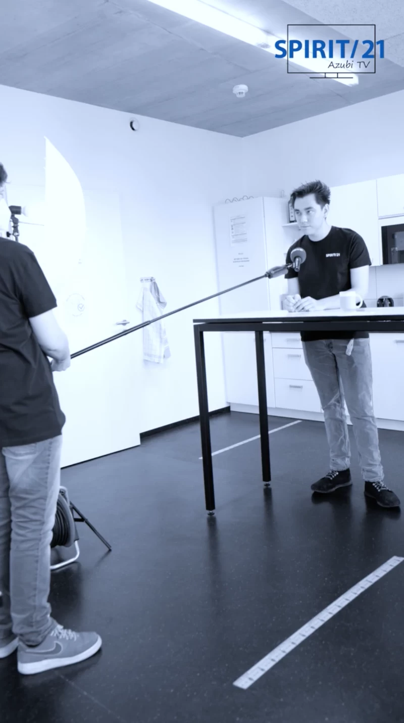 Ein Mann spricht in ein Mikrofon. Im Hintergrund ist eine K&uuml;che | SPIRIT/21