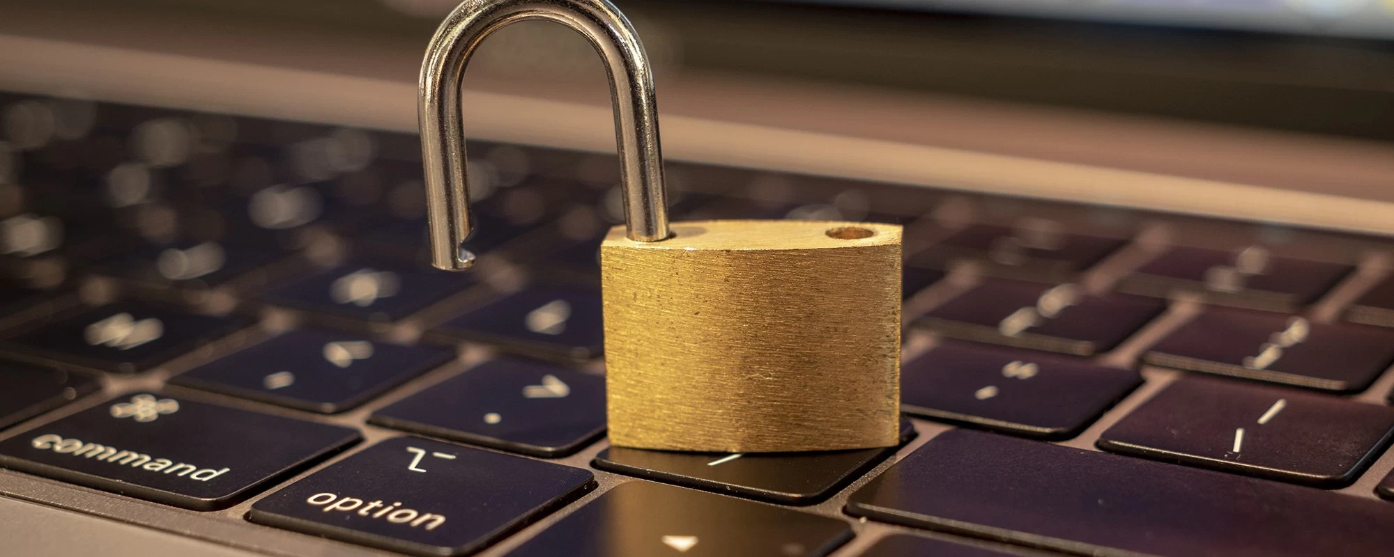 Ein offenes Vorh&auml;ngeschloss steht auf einer Apple Mac Tastatur eines Macbooks | SPIRIT/21